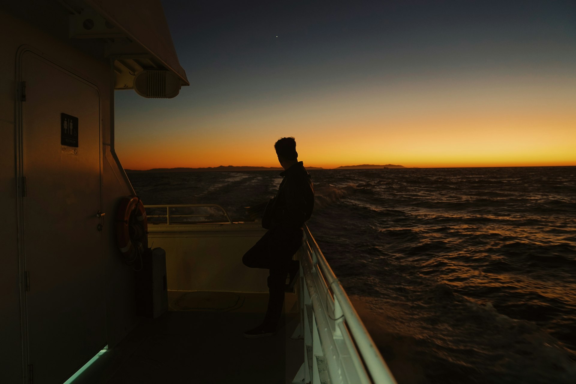 Marítimo no convés observando o horizonte ao pôr do sol