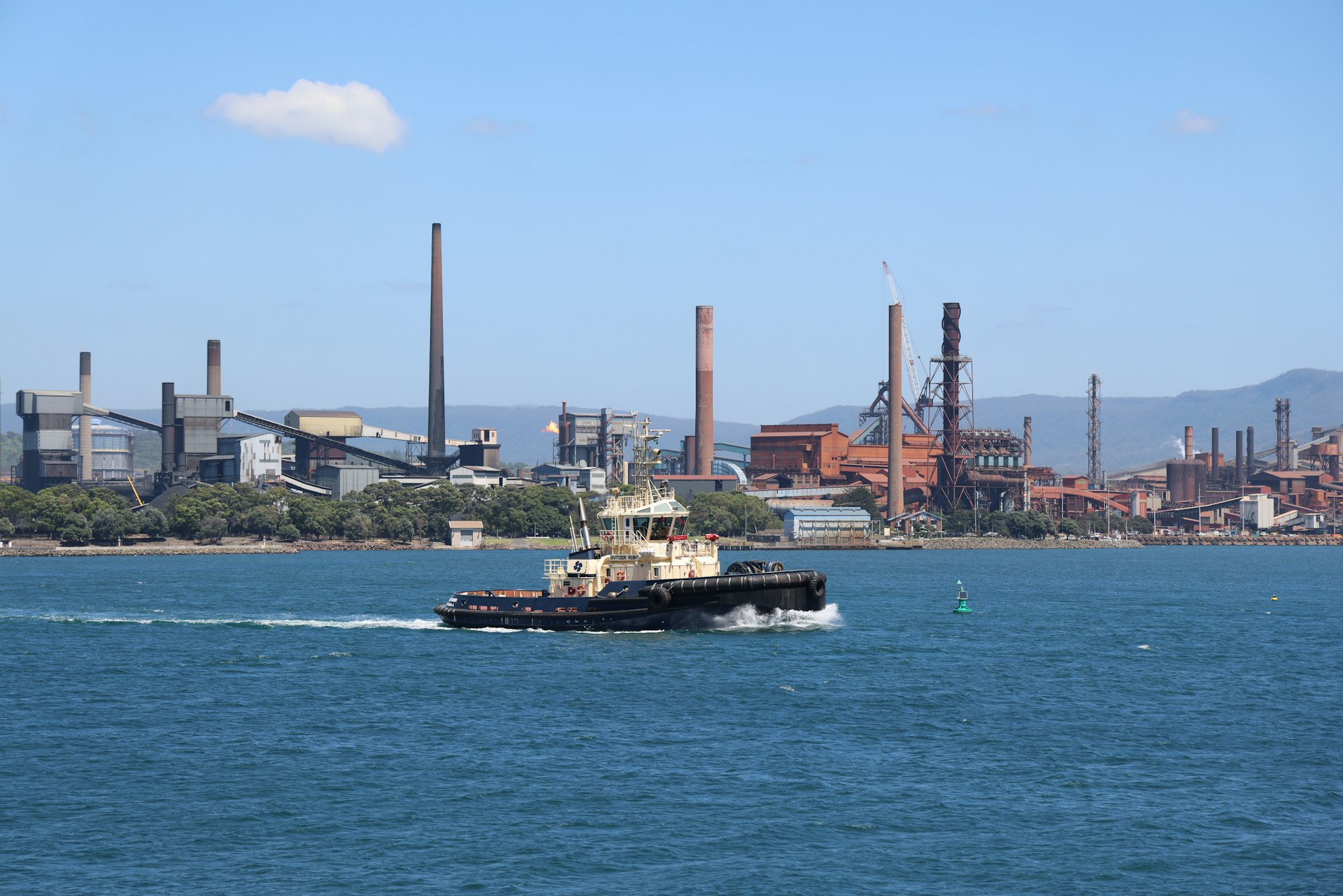 Rebocador navegando em zona portuária industrial