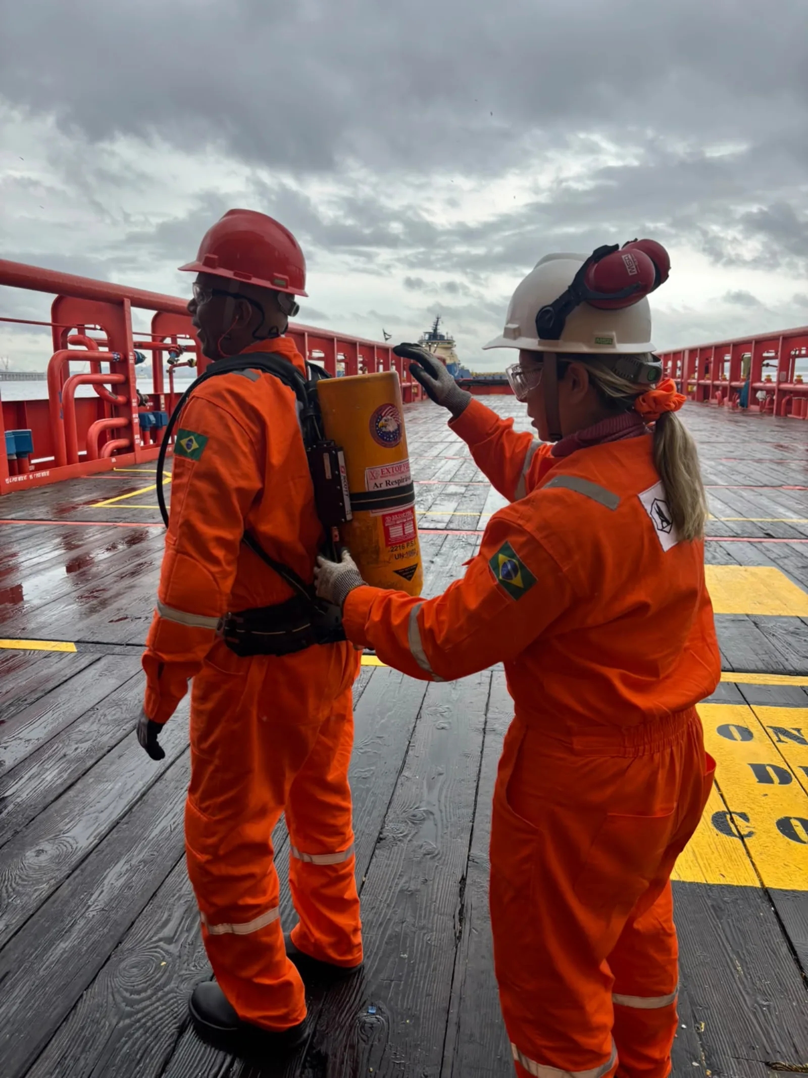 Equipe manuseando equipamento de respiração durante treinamento de segurança a bordo, parte da capacitação em NR-33
